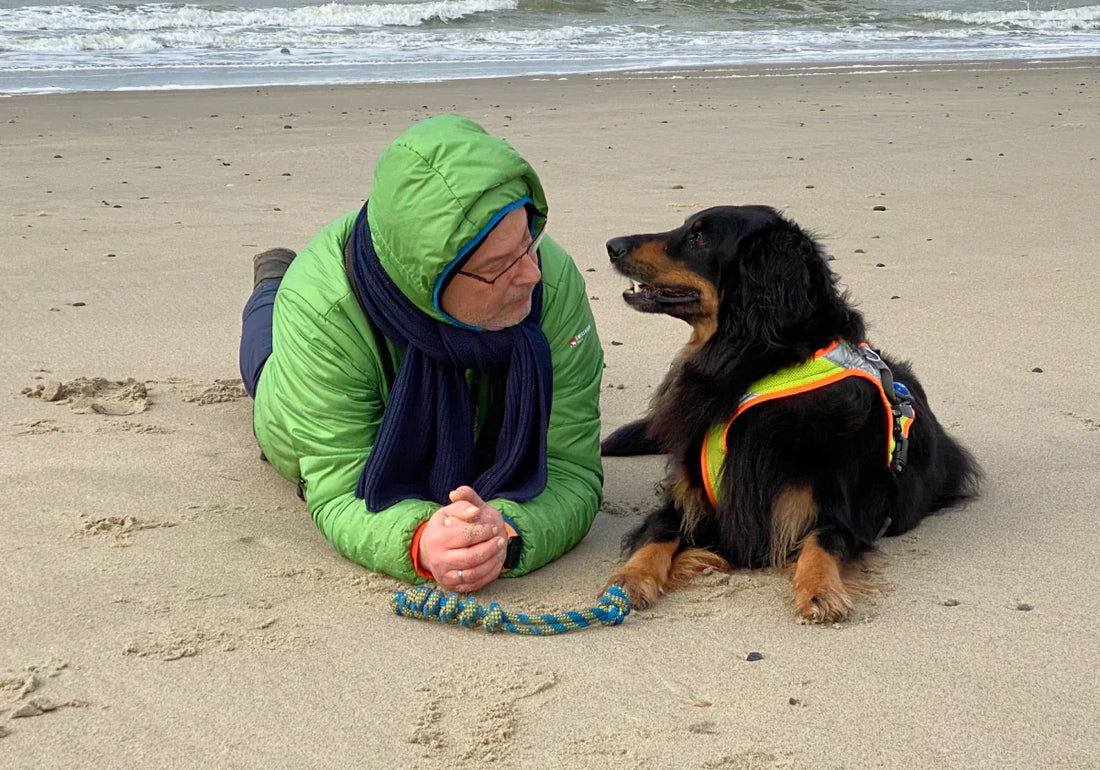 Alexander Laubenthal und Hovawart Hündin Aila liegen am Strand