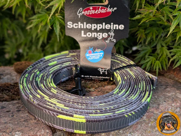 Aufgerollte schwimmfähige Grossenbacher Schleppleine mit Tarnmuster und Produktetikett auf Stein.