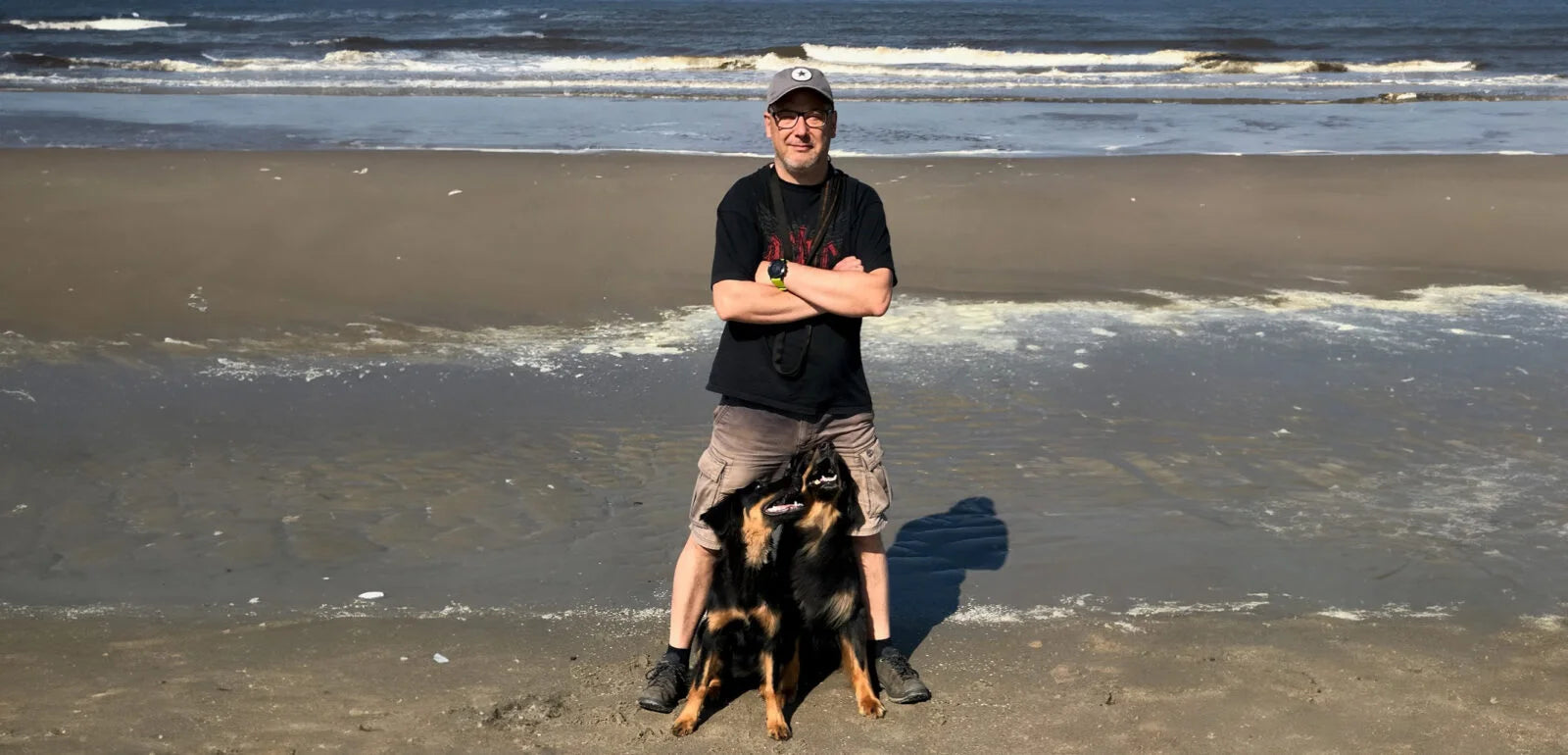 Mann mit großem Hund am Strand