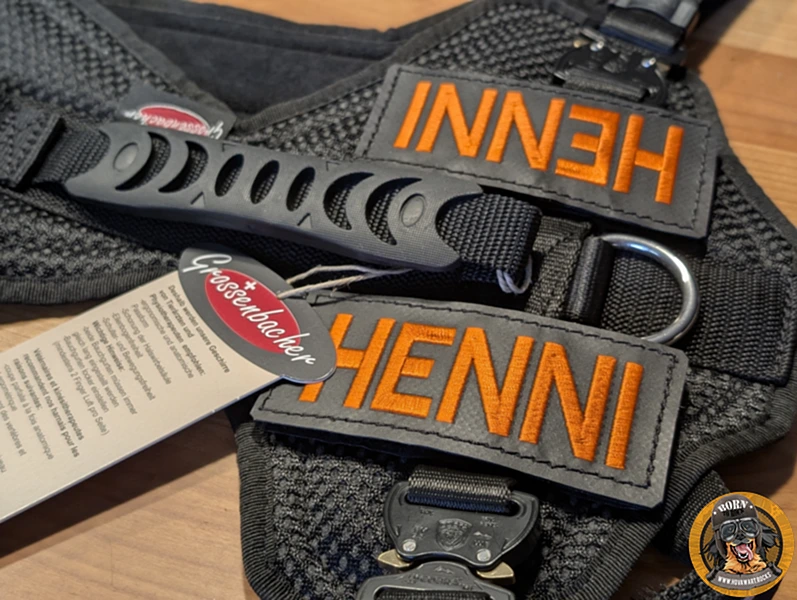Nahaufnahme eines rechteckigen, stabil bestickten Patches in Schwarz. Auf dem Patch steht in kontrastreicher, orangner Schrift der Name 